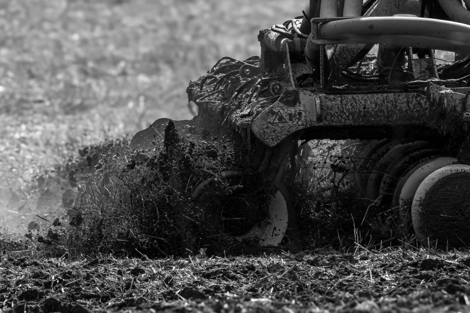 Black and white photo of machinery tilling soil, showcasing agriculture technology.